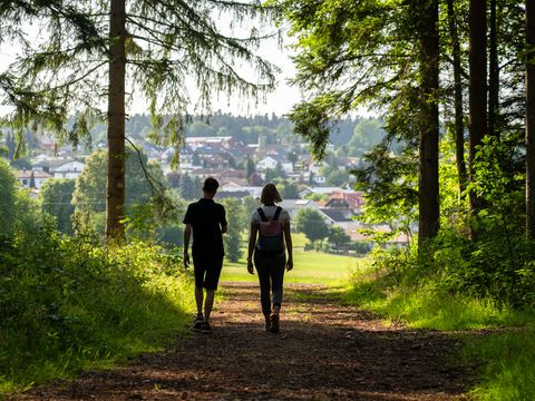 Paar beim Wandern aus dem Wald in Richtung Ortskern